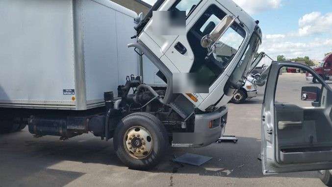 Cab-over box truck with the cab tilted forward for engine work