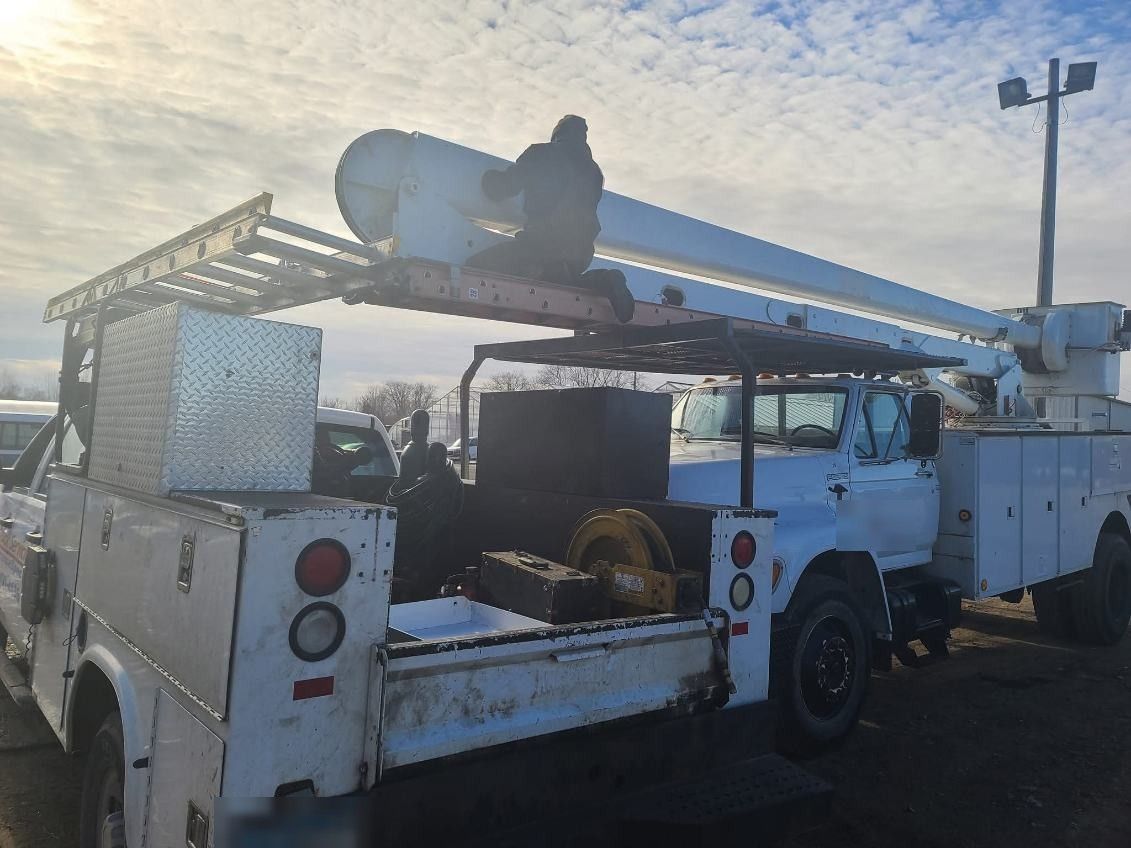 Utility boom truck being serviced on-site in a fleet yard