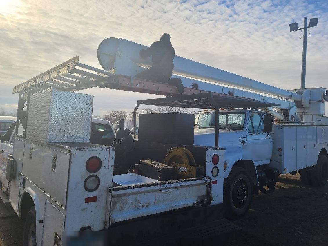 Utility boom truck being serviced on-site in a fleet yard